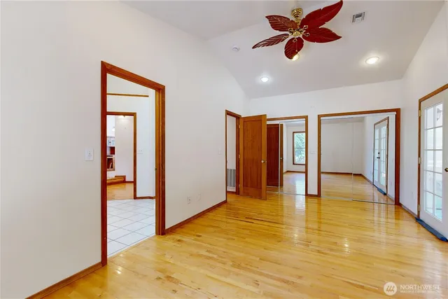 a view of an empty room and window with a ceiling fan
