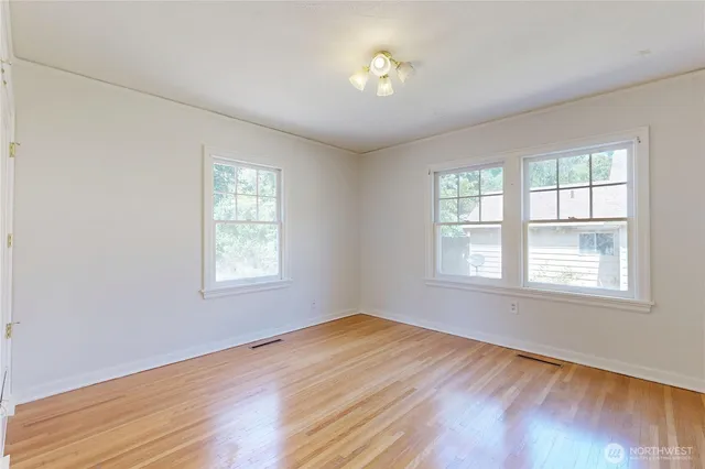 a view of empty room with wooden floor and fan