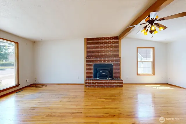 an empty room with windows and fireplace