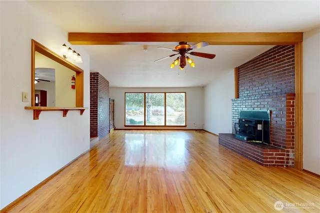 a view of an empty room with wooden floor and a fireplace