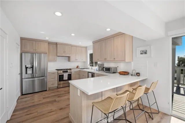 a kitchen with a refrigerator a sink dishwasher and a stove with wooden floor