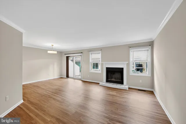 an empty room with wooden floor fireplace and windows