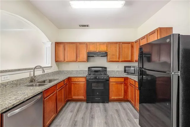 a kitchen with stainless steel appliances granite countertop wooden floor sink stove and refrigerator