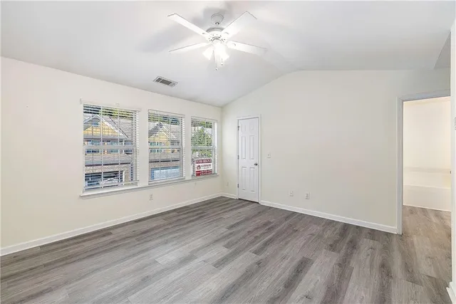 an empty room with wooden floor and ceiling fan