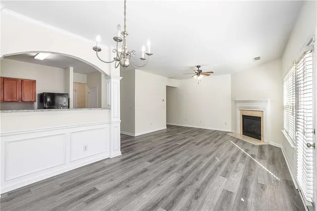 a view of a hallway with wooden floor and a kitchen space