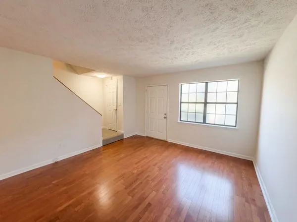 an empty room with wooden floor and windows