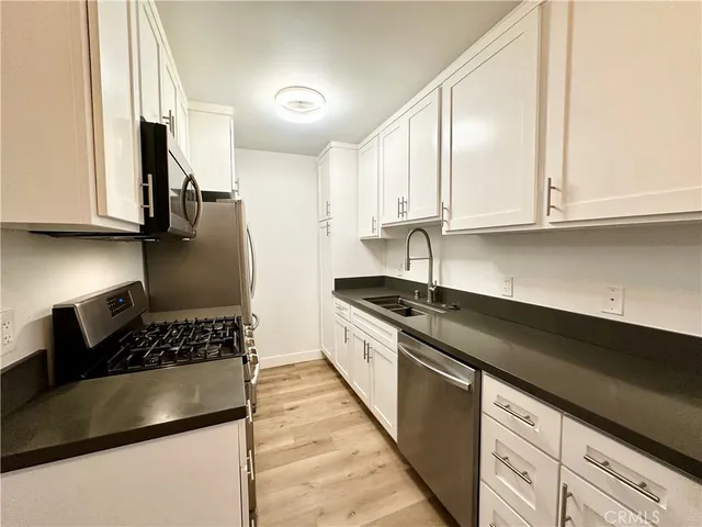 a kitchen with granite countertop a sink a stove and cabinets