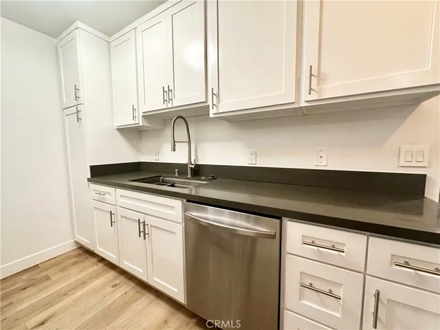 a kitchen with stainless steel appliances granite countertop white cabinets and a sink