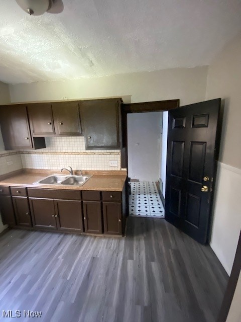 1843 Reyburn Road Cleveland, OH 44112 - Photo 3 of 39 Kitchen featuring backsplash, dark brown cabinets, a textured ceiling, sink, and dark hardwood / wood-style floors