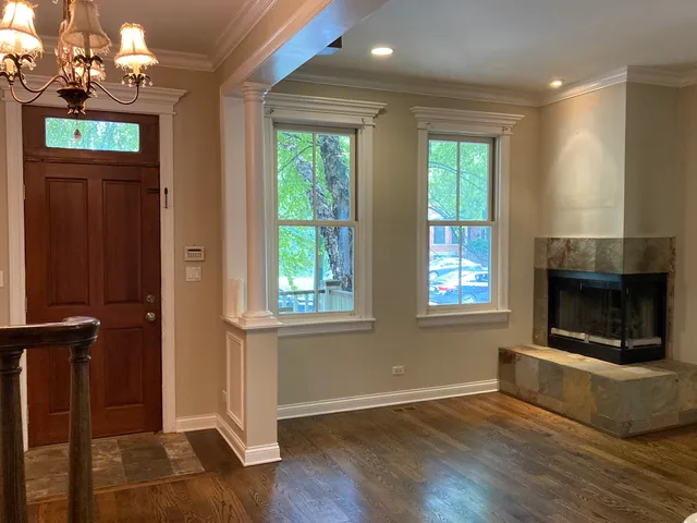 a view of an empty room with wooden floor fireplace and a window