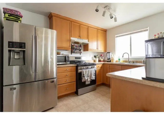 a kitchen with stainless steel appliances granite countertop a refrigerator a stove a sink dishwasher and a refrigerator with wooden floor