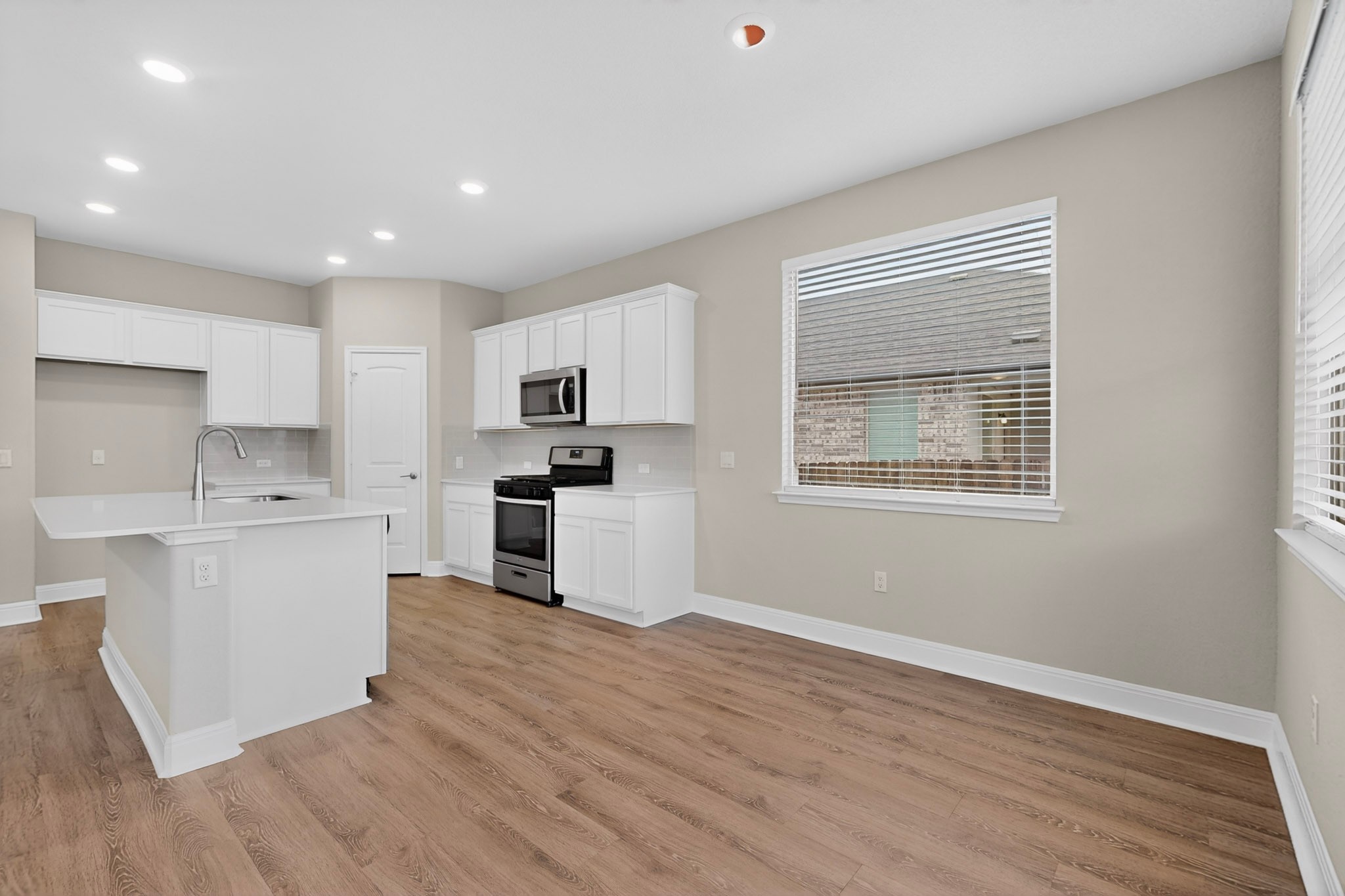 16809 Guido Cove Pflugerville, TX 78660 - Photo 9 of 40 Open-concept kitchen and living area featuring wood-finish flooring, recessed lighting, and white cabinetry