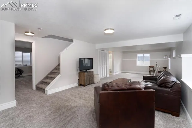 a living room with furniture a flat screen tv and a refrigerator