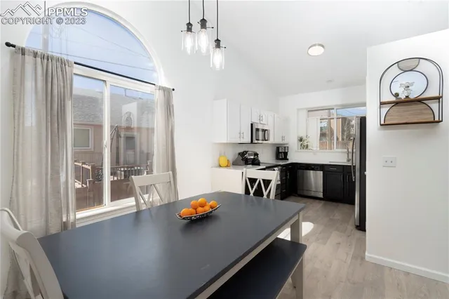 a open kitchen with stainless steel appliances granite countertop a stove a refrigerator a oven a dining table and chairs with wooden floor