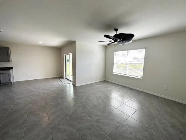 an empty room with windows and ceiling fan