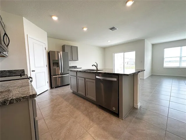 a kitchen with stainless steel appliances granite countertop a stove top oven a sink and a refrigerator