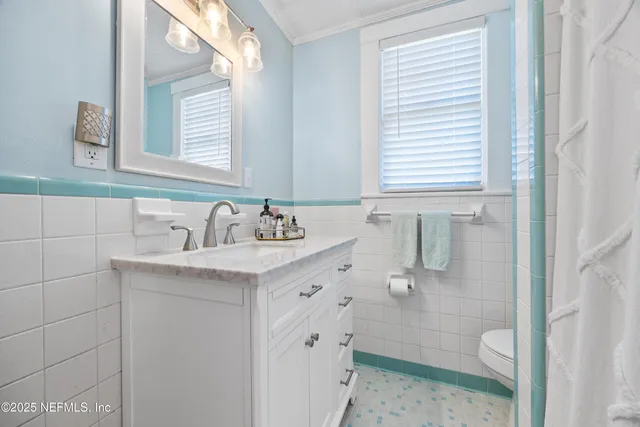 a bathroom with a granite countertop sink toilet a large mirror a shower and a window