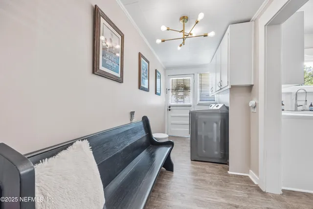 a living room with stainless steel appliances furniture a chandelier and a view of kitchen