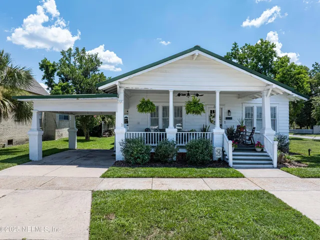 a front view of a house with a yard and potted plants