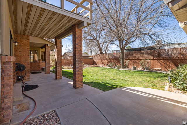 892 Cambridge Drive St. George, UT 84770 - Photo 64 of 65 Covered patio with brick columns and a slatted wood ceiling, extending to a concrete walkway