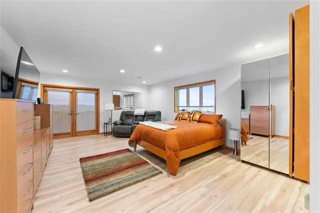 a spacious bedroom with a bed a couch and large window