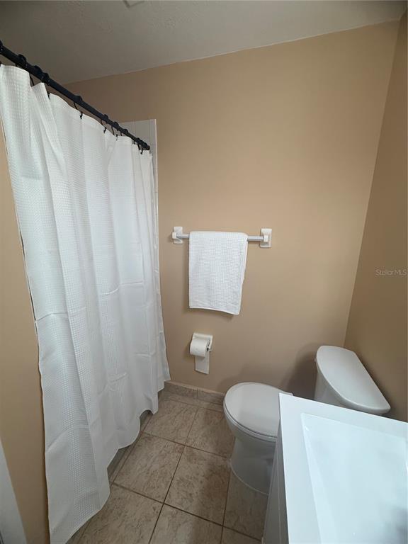 11707 Raintree Village Boulevard, Unit C Temple Terrace, FL 33617 - Photo 16 of 31 a bathroom with a toilet and a shower curtain