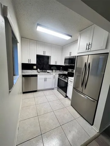 a kitchen with granite countertop a refrigerator and a stove top oven