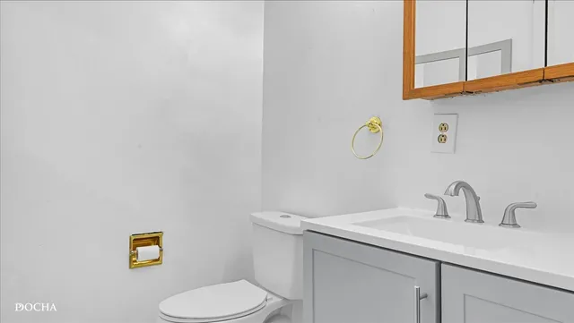 a bathroom with a toilet sink vanity and mirror