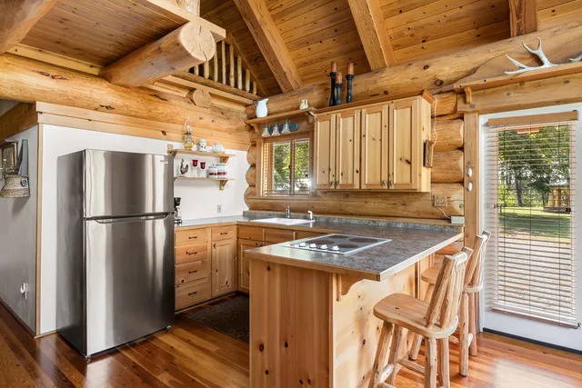 a kitchen with stainless steel appliances granite countertop a refrigerator a sink dishwasher a stove and a dining table with wooden floor