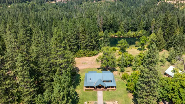 an aerial view of residential house with outdoor space and trees all around