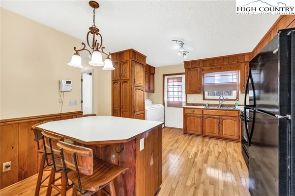 a kitchen with stainless steel appliances a stove a refrigerator a oven a sink with island and chairs