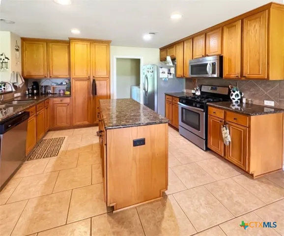 a kitchen with stainless steel appliances granite countertop a stove a sink and a microwave