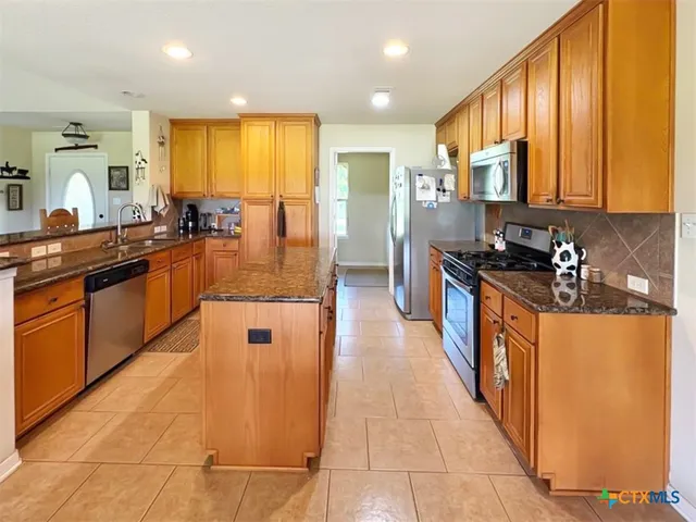 a kitchen with stainless steel appliances granite countertop a stove a sink dishwasher and a refrigerator