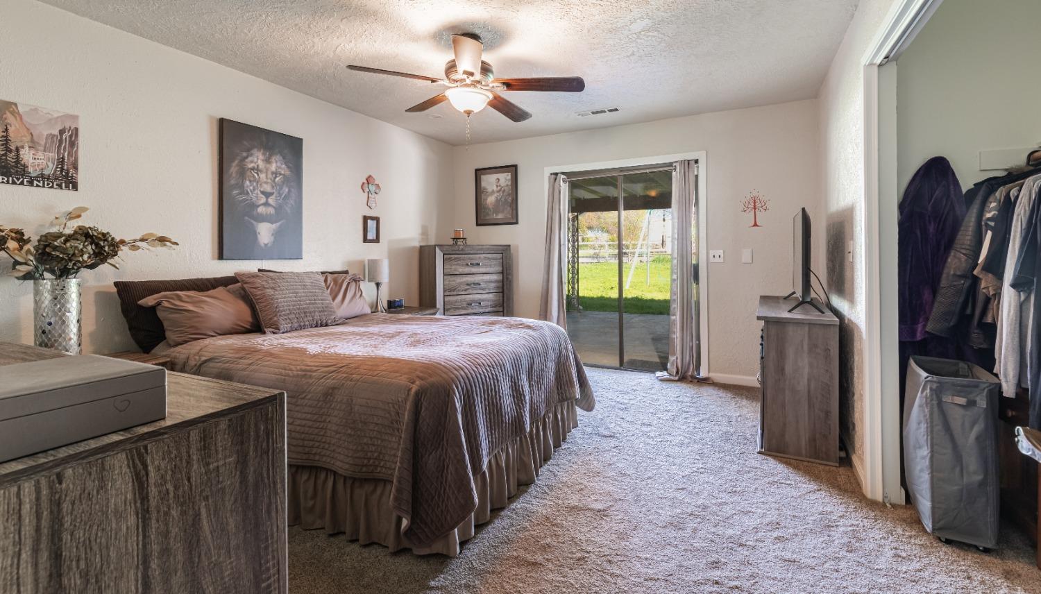 16993 Jennifer Court Madera, CA 93636 - Photo 20 of 55 a spacious bedroom with a bed a chandelier and a flat screen tv