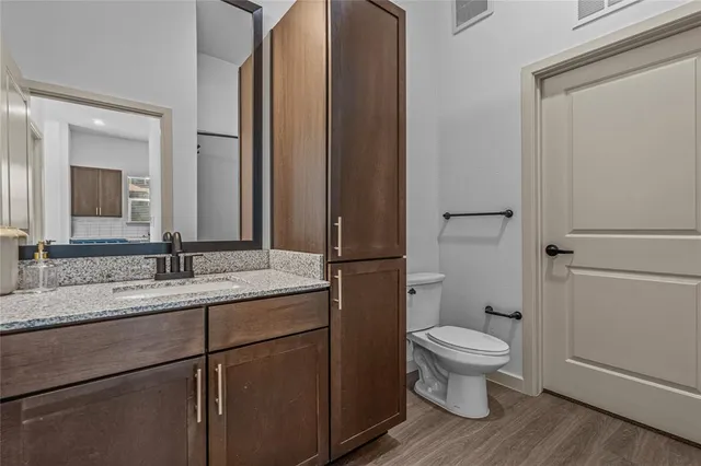 a bathroom with a granite countertop toilet sink and mirror