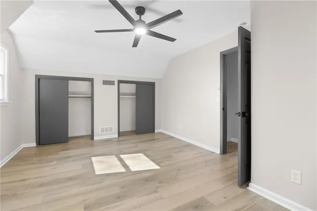 an empty room with wooden floor and ceiling fan
