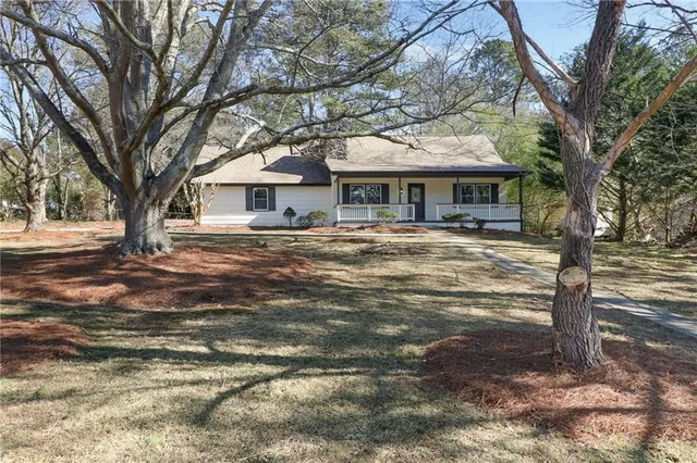 a front view of a house with a yard and large trees