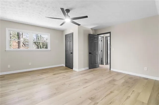 an empty room with wooden floor ceiling fan and windows