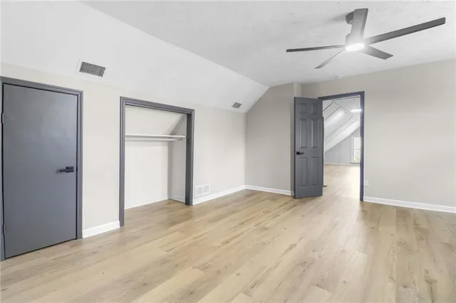 an empty room with wooden floor ceiling fan and windows