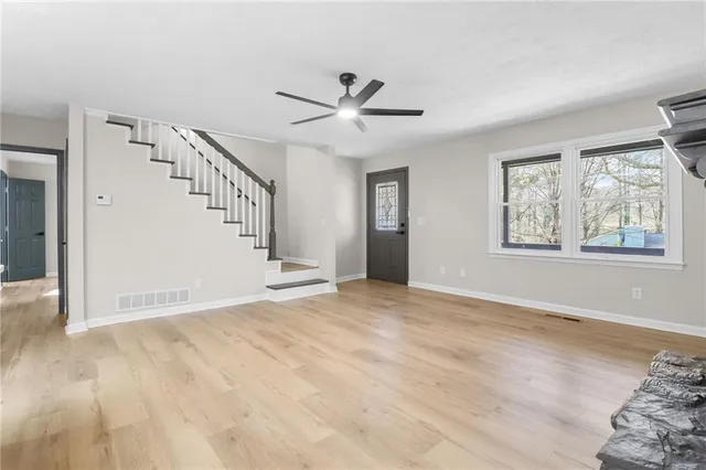 a view of an empty room with wooden floor and a ceiling fan