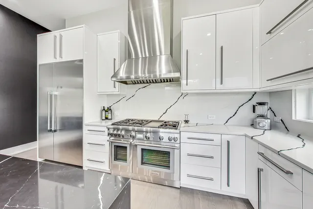 a kitchen with granite countertop a stove a sink and white cabinets