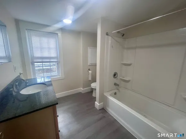 a bathroom with a granite countertop sink a toilet and bathtub