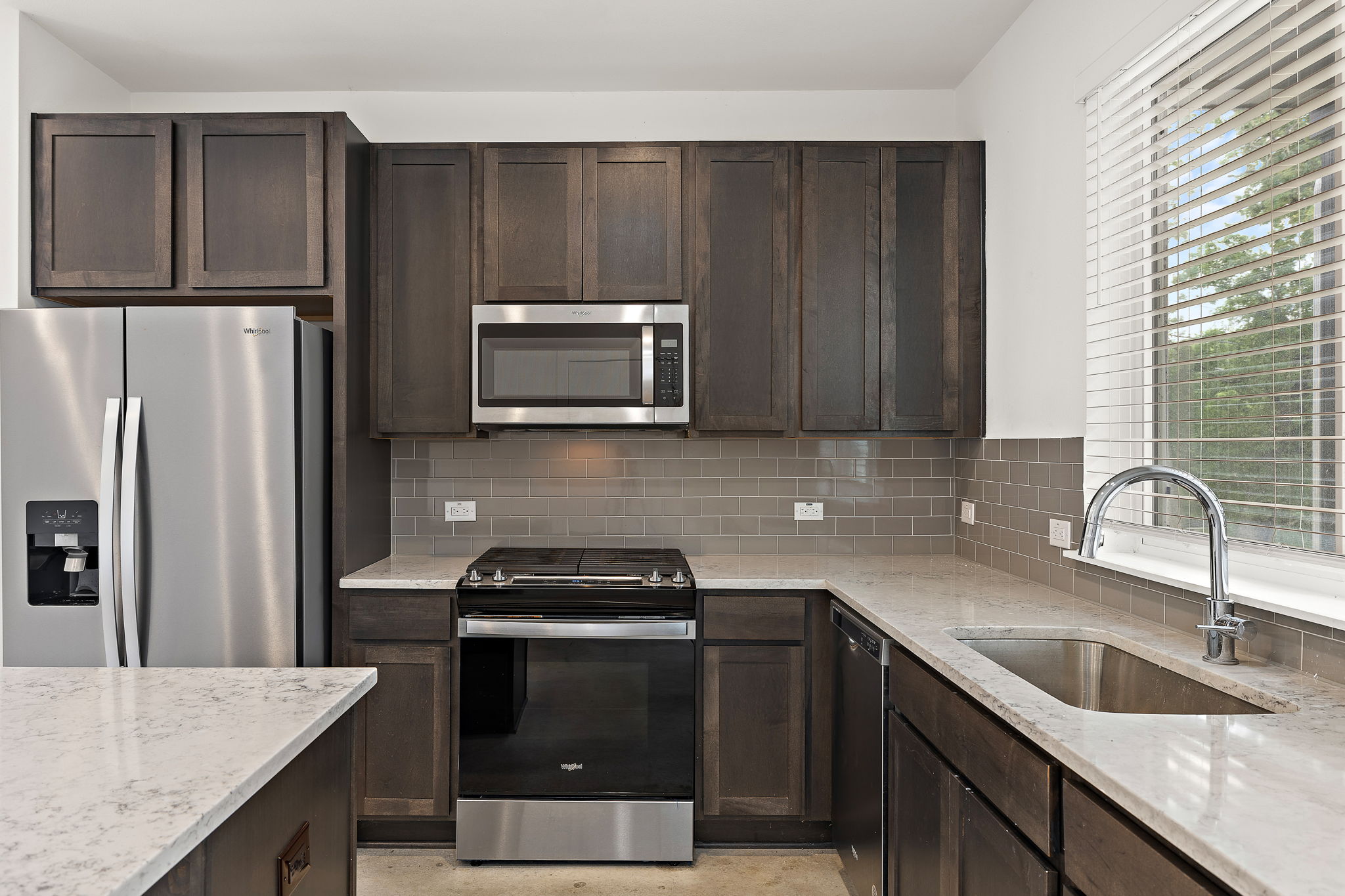 1206 Sarabeth Way Austin, TX 78721 - Photo 13 of 27 Kitchen featuring backsplash, dark brown cabinets, stainless steel appliances, and a sink
