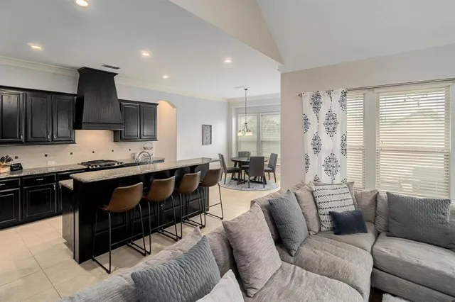 a living room with furniture a kitchen view and a window