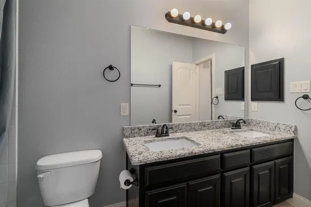 a bathroom with a granite countertop toilet sink and mirror