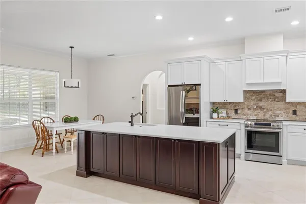 a kitchen with stainless steel appliances granite countertop a stove top oven a sink dishwasher a dining table and chairs with wooden floor