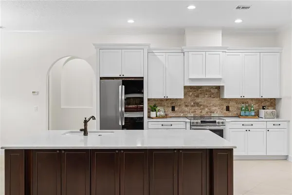 a kitchen with stainless steel appliances granite countertop a sink a stove and white cabinets