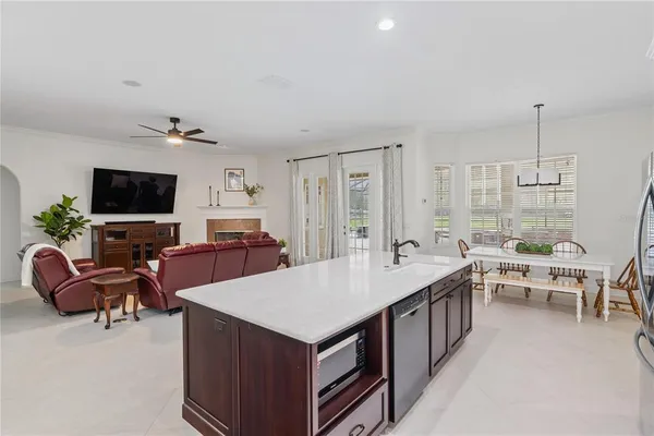 a large living room with stainless steel appliances kitchen island granite countertop a table chairs in it and a flat screen tv