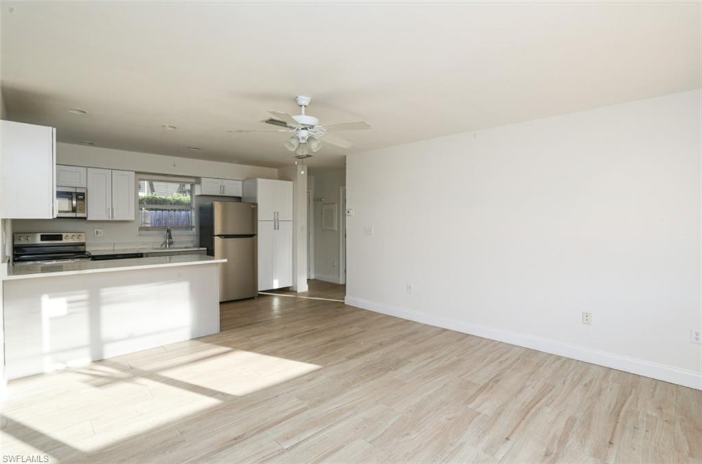 524 97th Avenue North, Unit B Naples, FL 34108 - Photo 7 of 13 a large kitchen with cabinets wooden floor and stainless steel appliances
