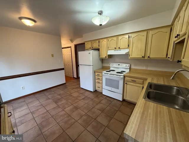 a kitchen with granite countertop a refrigerator a sink dishwasher and white cabinets next to a window